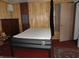 Bedroom with bare mattress, wood paneled walls, and standard doorway at 1722 N Parker Ave, Indianapolis, IN 46218