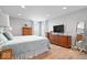 Bright bedroom with wood floors, large dresser with TV, and standing mirror at 19546 Forsythe Dr, Noblesville, IN 46060