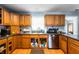 This kitchen features wood cabinets, black appliances, laminate countertops, a stainless sink and vinyl flooring at 20892 Overdorf Rd, Noblesville, IN 46062