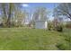 Backyard featuring a storage shed, lush green lawn, and mature trees at 2631 Collier St, Indianapolis, IN 46241