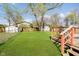 Spacious backyard with a wooden deck, lush green grass, storage sheds, and a chain-link fence at 3414 Arbor Ave, Indianapolis, IN 46217
