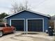 Detached two-car garage with dark doors and blue siding, with an orange car parked outside at 389 W Poston Rd, Martinsville, IN 46151