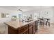 Kitchen island featuring a double sink, dark wood cabinets, and an adjacent dining area and living room at 5083 Castamere Dr, Noblesville, IN 46062
