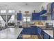 Well-lit kitchen featuring stainless steel appliances, farmhouse sink, blue cabinets, and a marble countertop island at 5157 Climbing Rose Pl, Indianapolis, IN 46254