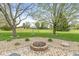 Cozy brick fire pit area with landscaping and mature trees in the background at 5298 Royal Troon Way, Avon, IN 46123