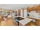 Open kitchen with light-colored countertops, wood cabinets and an island cooktop with a view of the dining area at 5341 W Stonehaven Ln, New Palestine, IN 46163