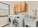 Bright laundry room with a sink, front load washer and dryer, cabinet, and a window at 5341 W Stonehaven Ln, New Palestine, IN 46163
