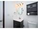 Well-lit half bathroom with a modern vanity, toilet, and wall cabinet for storage at 5424 Milhouse Rd, Indianapolis, IN 46221