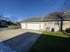 Three car attached garage with an extra parking pad and lush green lawn at 5441 Red Hawk Ln, Greenwood, IN 46142