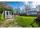 View of the backyard and small shed, featuring a large green lawn and partial fence at 5442 Hibben Ave, Indianapolis, IN 46219