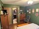 Green bedroom with a bathroom view, wooden dresser, and floral decor at 5626 Hammon Dr, Brownsburg, IN 46112