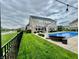 An open backyard is shown with a pool, patio furniture, green grass, and a wrought iron fence at 5802 Bentbrook Dr, Bargersville, IN 46106