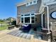 The image shows an outdoor patio space with stylish furniture, a large window, and a view of the manicured lawn at 5802 Bentbrook Dr, Bargersville, IN 46106