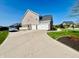 A long driveway to a gray home with a three car garage and lovely landscaping at 5802 Bentbrook Dr, Bargersville, IN 46106