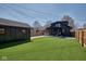 Expansive backyard with a dark house, pergola with modern furniture, and artificial turf at 6173 Rosslyn Ave, Indianapolis, IN 46220