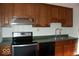 Galley kitchen featuring wood cabinets, black appliances, and a stainless steel sink at 7838 Burr Oak Ct, Indianapolis, IN 46217