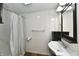 Bright bathroom showcasing a walk-in shower with a gray curtain, white panel walls, and a sleek vanity with a modern sink at 831 N 12Th St, Elwood, IN 46036