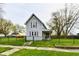 Charming two-story home featuring a fenced yard, covered porch, and traditional architecture with red shutters at 831 N 12Th St, Elwood, IN 46036