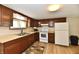 Kitchen featuring wooden cabinets, beige countertops, white appliances, and a stainless steel sink at 831 N 12Th St, Elwood, IN 46036