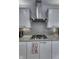 Close up of stovetop with custom backsplash and cabinetry at 8740 Morgan Dr, Fishers, IN 46038