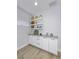 Bright living area with white cabinets, gray countertop, floating shelves, and light wood floors at 8740 Morgan Dr, Fishers, IN 46038