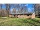 Brick home's rear exterior showcasing a dark wood deck and a spacious, well-manicured lawn at 9882 Woodbriar Ln, Carmel, IN 46280