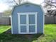 Close-up of shed with double doors and white trim against a backdrop of a grassy lawn and fence at 99 Armitage St, Cicero, IN 46034
