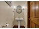 Stylish powder room with a pedestal sink, decorative mirror, and wood door at 10814 Tallow Wood Ln, Indianapolis, IN 46236