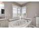 Bright bathroom featuring a soaking tub with jets, a large window, and a vanity at 10846 Hamilton Pass, Fishers, IN 46037