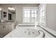 Bright bathroom featuring a soaking tub with jets, a gray tiled backsplash, a white vanity and large window at 10846 Hamilton Pass, Fishers, IN 46037