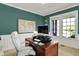 Inviting office features bright windows, teal walls, a world map, and a classic wooden desk with a modern computer setup at 11509 Wildlife Ct, Zionsville, IN 46077