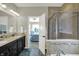 Well-lit bathroom with double sinks, granite counters, glass shower and soaking tub, and view to bedroom at 11685 Platt St, Noblesville, IN 46060