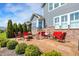 Inviting backyard patio with brick accents, a fire pit, lush landscaping, and comfortable red seating for relaxing outdoors at 11685 Platt St, Noblesville, IN 46060