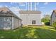 View of the backyard with gray siding house, showing the patio and detached garage under a sunny sky at 13 N Main St, Brooklyn, IN 46111