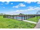 Community pool is surrounded by a black fence, green space, and a shaded structure with a beautiful blue sky above at 1581 S 825 E, Zionsville, IN 46077