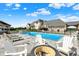 Backyard pool area featuring a fire pit, lounge chairs, a covered patio and a large home in the background at 1581 S 825 E, Zionsville, IN 46077