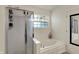 Bright bathroom with a glass-enclosed shower and a soaking tub under a window, perfect for relaxation at 15890 Concert Way, Noblesville, IN 46060