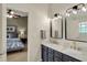 Bathroom featuring a double sink vanity with modern lighting and gold fixtures, with view of the bedroom at 15890 Concert Way, Noblesville, IN 46060