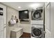 Compact laundry room with stacked washer and dryer, complemented by a storage bench and wall cabinets at 15890 Concert Way, Noblesville, IN 46060