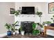 Cozy fireplace with white brick and a decorative mantel, surrounded by plants at 1646 Fisher Ave, Indianapolis, IN 46224