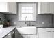 Bright kitchen featuring farmhouse sink, mosaic backsplash, and modern white cabinetry at 1646 Fisher Ave, Indianapolis, IN 46224
