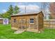 Rustic wood shed with a metal roof, windows, and double doors in a lush, green backyard at 1707 Lafayette Ave, Lebanon, IN 46052