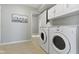 The laundry room includes a washer, dryer, upper cabinets, and neutral tile flooring at 17777 Crown Pointe Ct, Noblesville, IN 46062