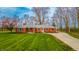 Charming red brick ranch home with a lush green lawn and mature trees at 1911 N Rangeline Rd, Anderson, IN 46012