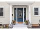 Welcoming entryway showcasing a stylish blue door flanked by potted plants and a 'HOME' welcome mat at 310 W 43Rd St, Indianapolis, IN 46208