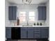 Bright kitchen with blue cabinets, stainless steel dishwasher, and ample counter space at 310 W 43Rd St, Indianapolis, IN 46208