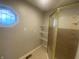 Neutral-toned bathroom featuring a glass door shower, geometric window, and wire shelving for storage at 3202 Acacia Dr, Indianapolis, IN 46214