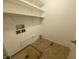 Laundry room with white walls, brown tile floor, and shelving unit for storage at 3202 Acacia Dr, Indianapolis, IN 46214