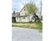 Two-story home with yellow siding, large yard and detached gravel parking space at 3502 N Illinois St, Indianapolis, IN 46208