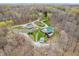 An aerial view showcases the green-roofed home nestled within a lush landscape of trees at 3504 Morgan Oaks Cir, Martinsville, IN 46151